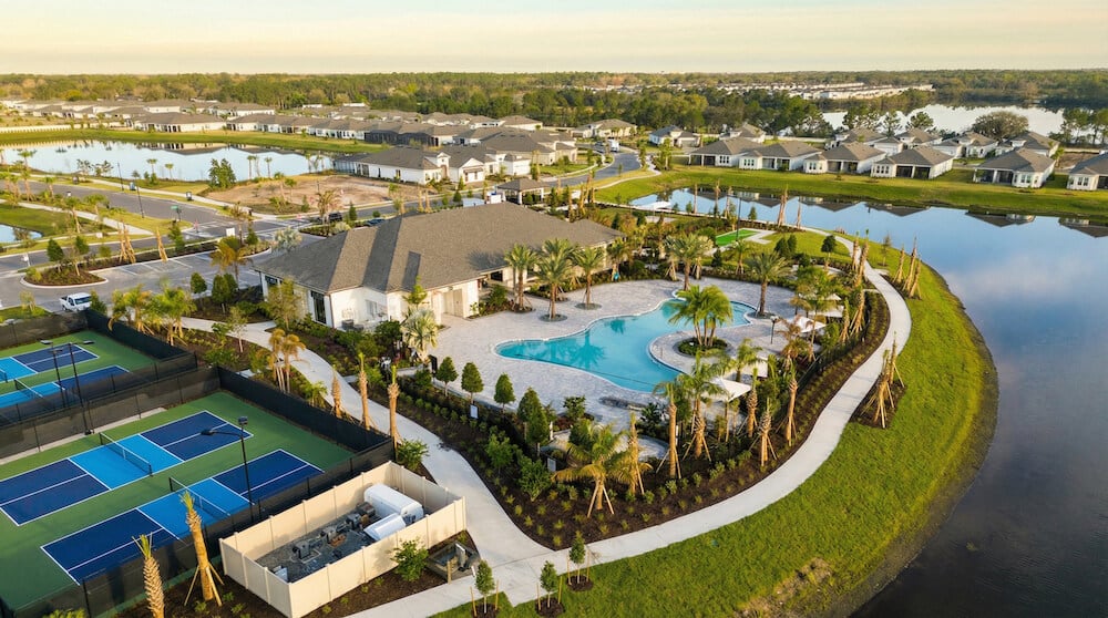 Aerial view of Esplanade at Center Lake Ranch featuring a resort-style pool, landscaped areas, tennis courts, and nearby homes in a master-planned community setting.