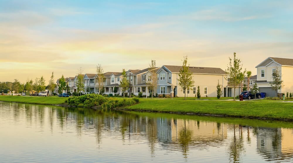 Residential homes along a serene lakefront, showcasing a mix of bungalows and single-family houses with well-maintained lawns and trees, reflecting a peaceful neighborhood atmosphere at Center Lake Ranch.